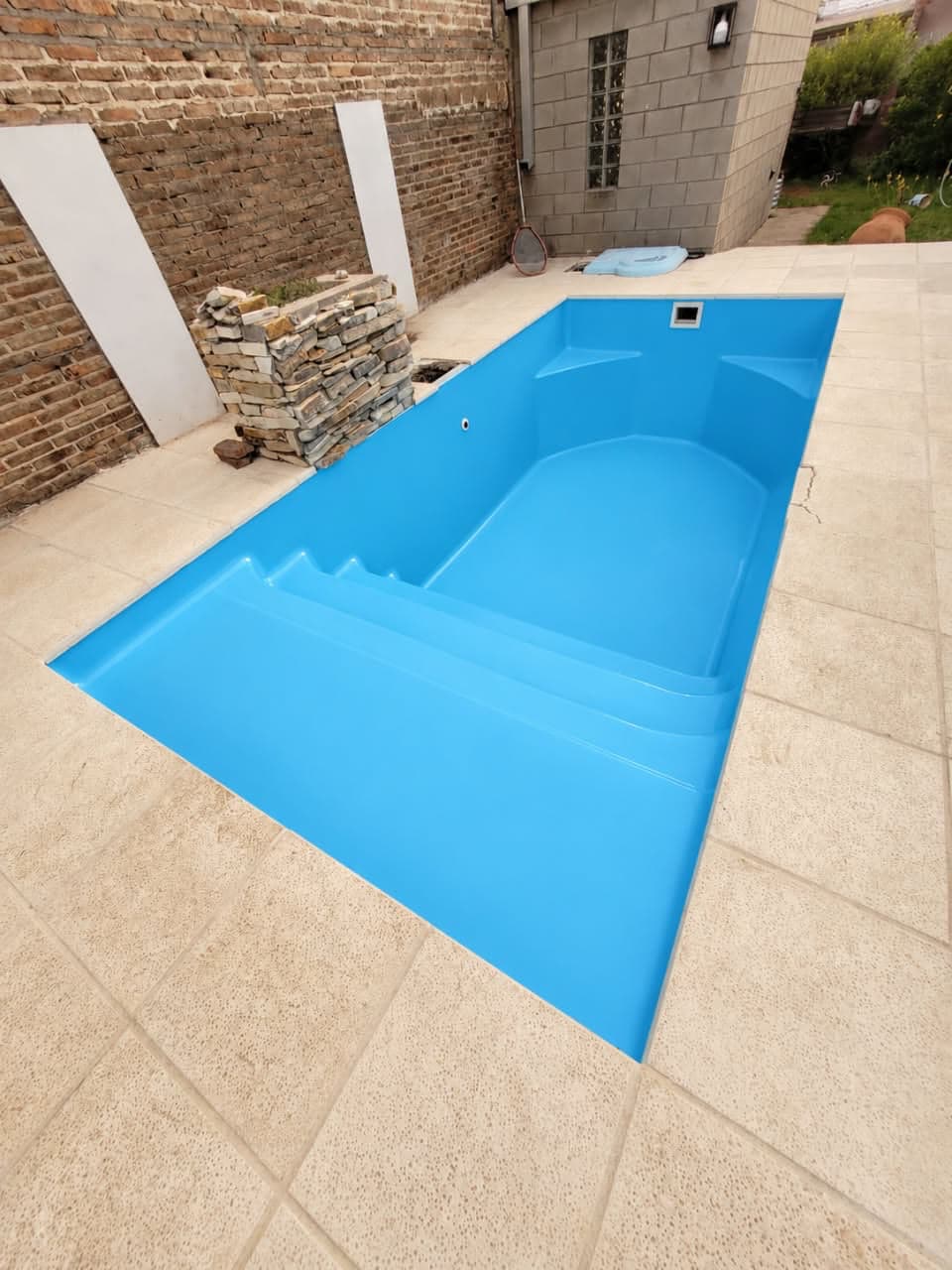 La misma piscina pintada de azul, con escalones y bancos nuevos