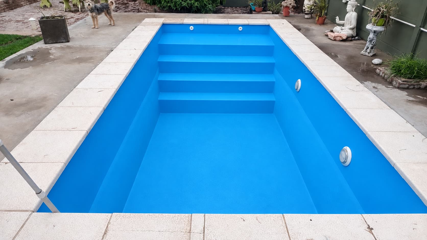 La misma piscina pintada con gel‑coat azul, escalones y luces