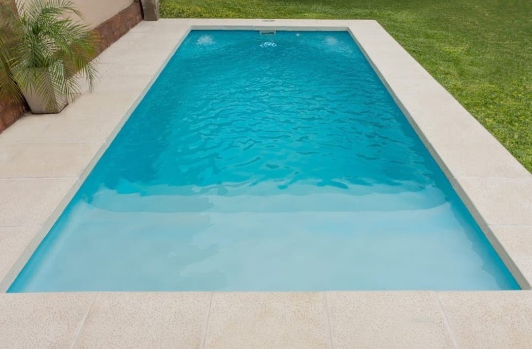 Piscina rectangular con borde atérmico junto al césped